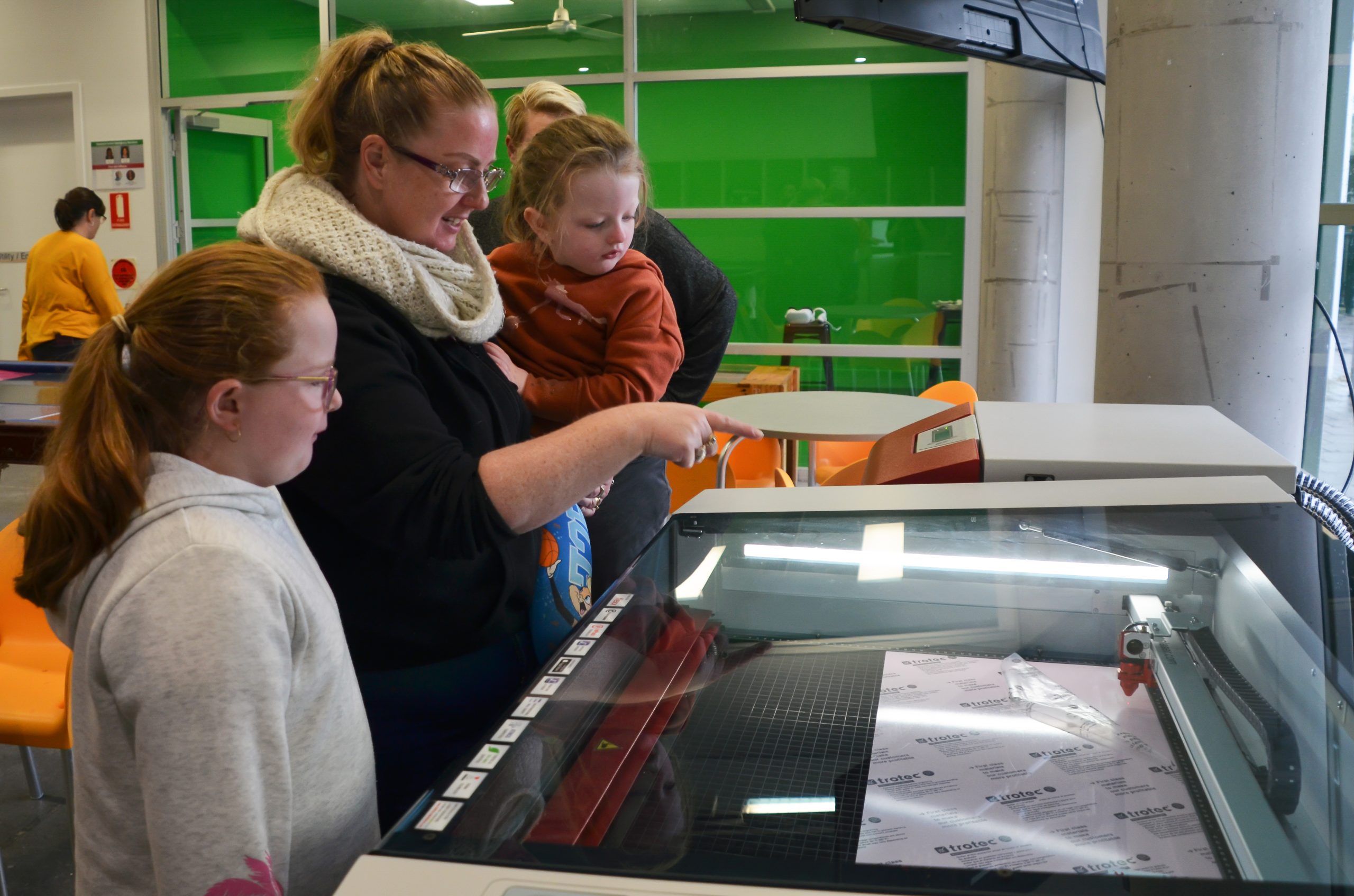 People looking at a laser cutter